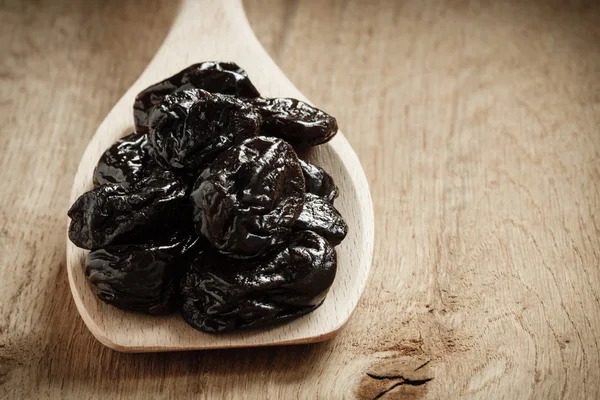 Prunes on wooden spoon — Stock Photo, Image