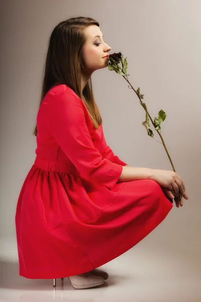 Mulher de vestido vermelho posando com rosa seca . — Fotografia de Stock