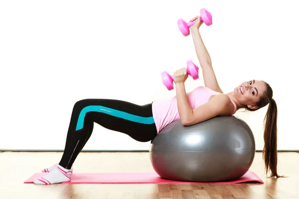 Kvinna med gym boll och dum klockor isolerade — Stockfoto