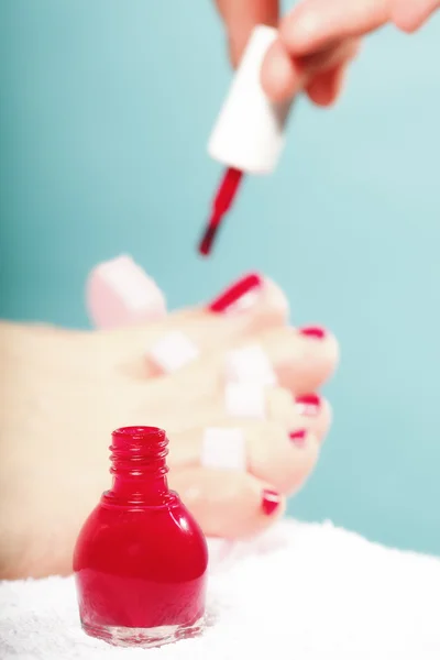 Fußpediküre mit roten Fußnägeln auf blauem Grund — Stockfoto