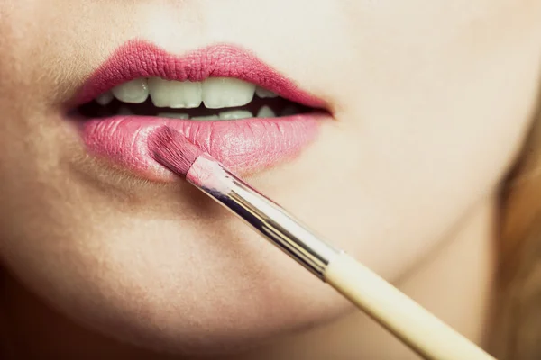 Frau trägt rosa Lippenstift mit Pinsel auf — Stockfoto
