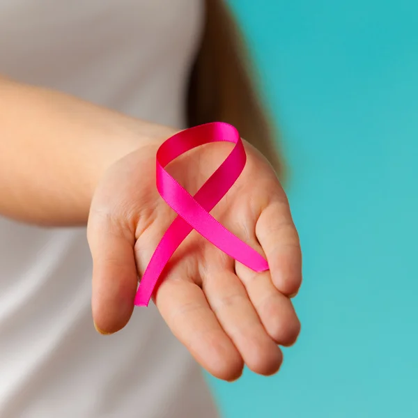 Pink breast cancer awareness ribbon on womans hands — Stock Photo, Image