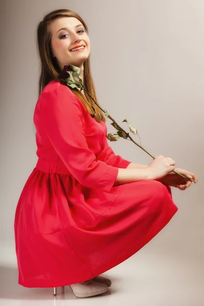 Mulher de vestido vermelho com rosa seca sorrindo — Fotografia de Stock