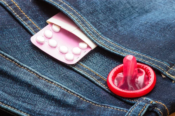 Pills and condom in denim pocket. — Stock Photo, Image