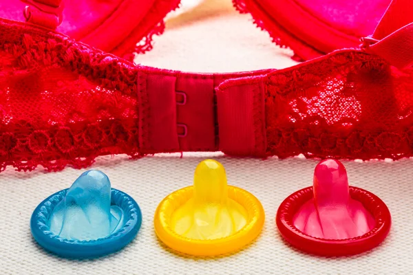 Барвисті презервативи і мереживний бюстгальтер . — стокове фото