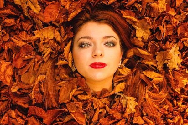 Jeune femme souriant dans les feuilles d'automne . — Photo