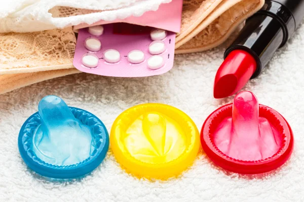 Pills condoms and lipstick on lace lingerie — Stock Photo, Image