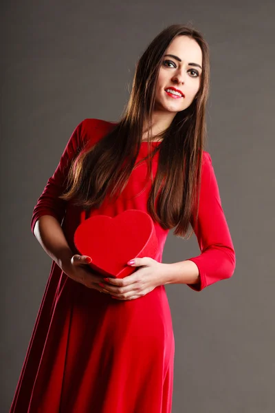 Mulher vestido vermelho contém caixa em forma de coração — Fotografia de Stock