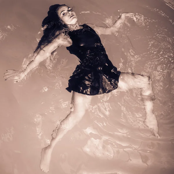 Woman floating on swimming pool in black dress. — Stock Photo, Image