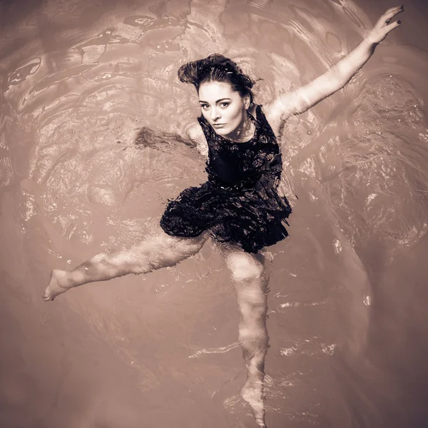 Kvinna som flyter på poolen i svart klänning. — Stockfoto