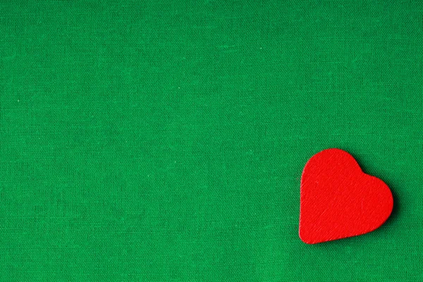 Красное сердце на зеленой ткани — стоковое фото