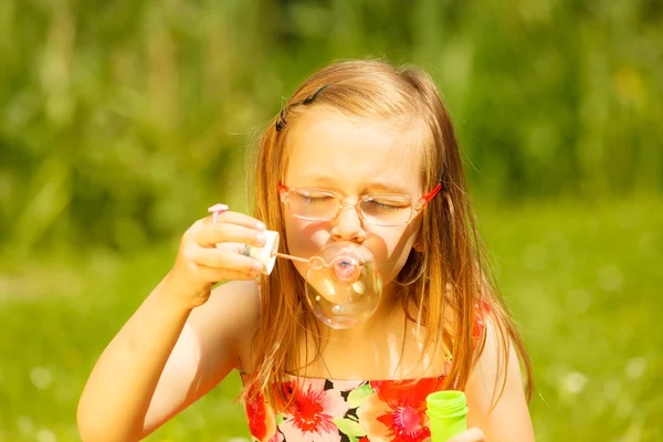 Girl blowing soap bubbles — Stock Photo, Image