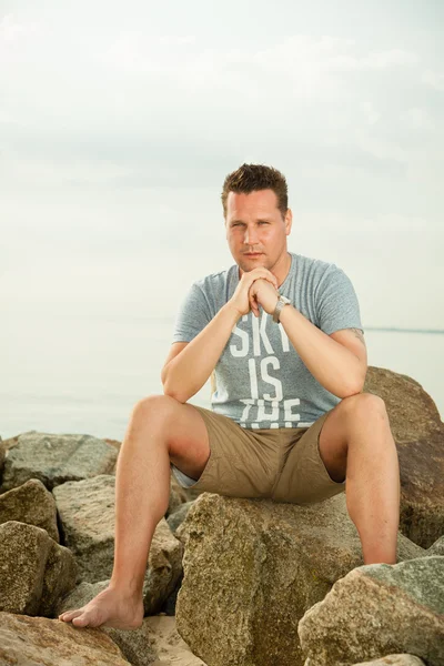 Uomo seduto sulla spiaggia — Foto Stock