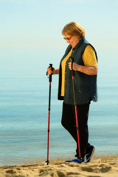 Aktive Seniorin beim Nordic Walking am Strand — Stockfoto