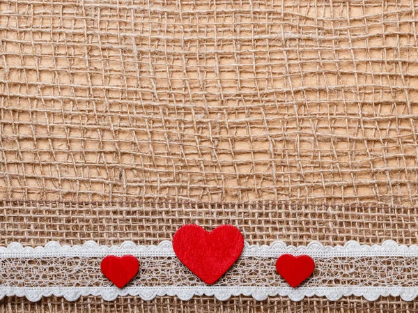 Red hearts on abstract cloth — Stock Photo, Image