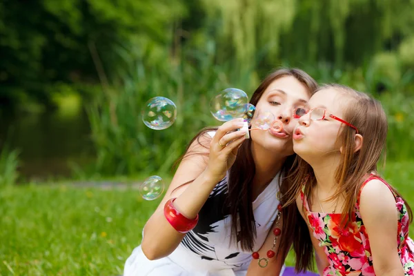 Mother blowing soap bubbles — Stock Photo, Image