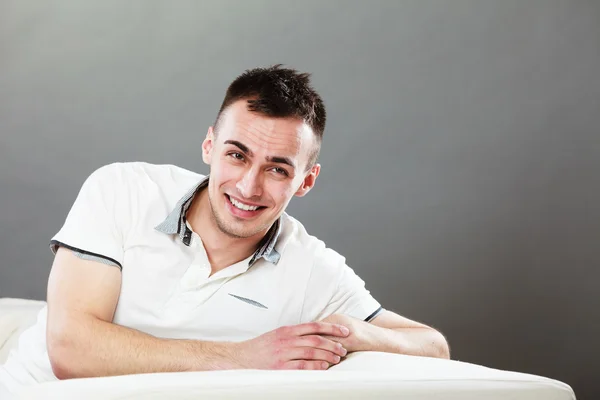 Jeune homme souriant relaxant sur le canapé — Photo