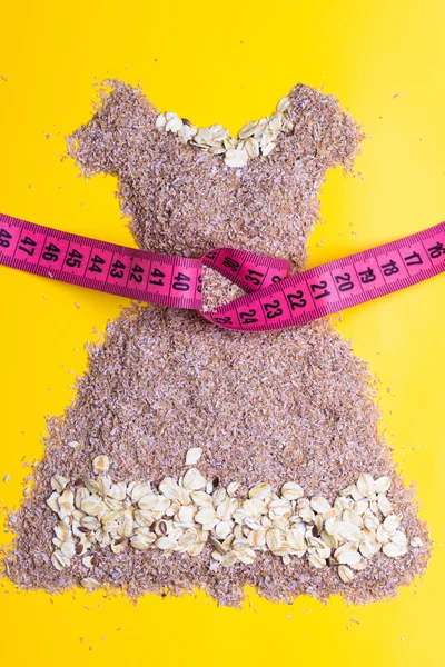 Dress shape made from bran with measure tape — Stock Photo, Image