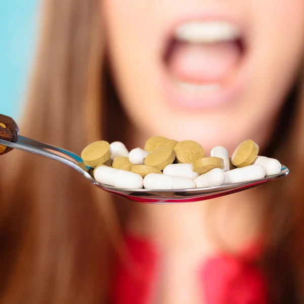 Young woman eating pills on a spoon — Stock Photo, Image