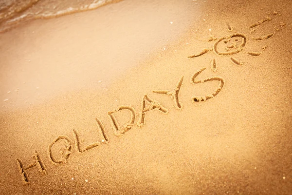 Vacaciones de palabras escritas en la arena en una playa — Foto de Stock