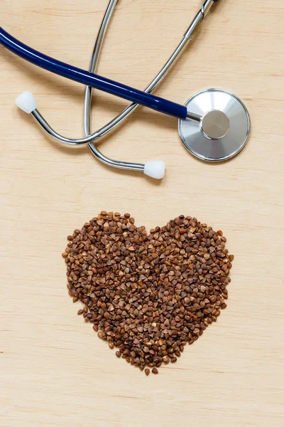 Buckwheat groats heart shaped on wooden surface. — Stock Photo, Image