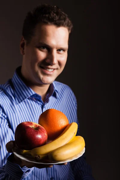 Ung man som håller frukt — Stockfoto