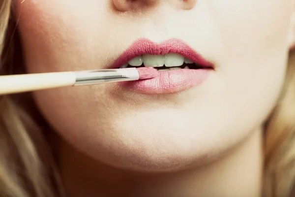 Vrouw roze lippenstift met borstel toepassen — Stockfoto