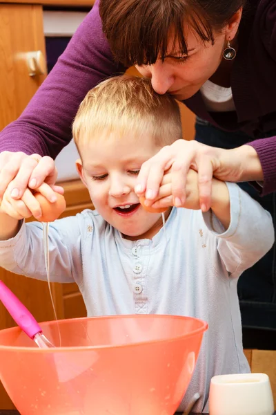 Little boy baking cake with mother, breaking egg. — Stock Photo, Image