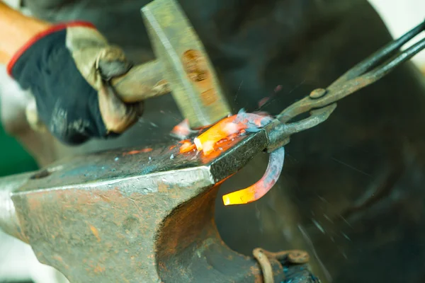 Blacksmith forges a hot horseshoe. — Stock Photo, Image