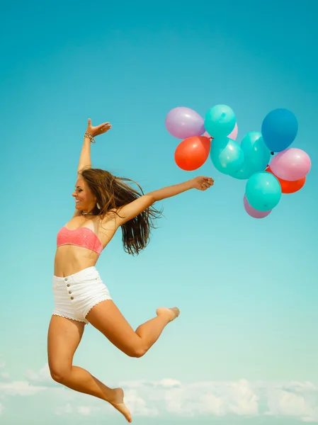 Meisje springen met kleurrijke ballonnen — Stockfoto