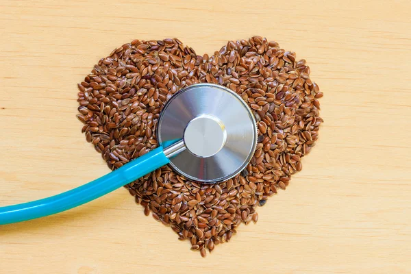 Syrová lněná semena ve tvaru srdce a stetoskop — Stock fotografie
