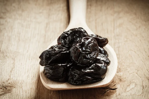 Dried plums prunes on wooden spoon — Stock Photo, Image