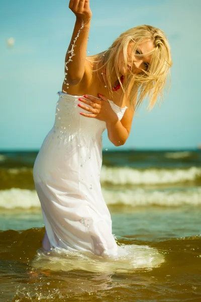Meisje in witte jurk die zich voordeed op strand. — Stockfoto