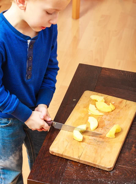 Kind schneidet Apfel mit Küchenmesser — Stockfoto