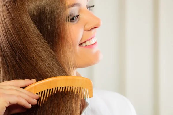 Женщина расчесывает длинные каштановые волосы — стоковое фото