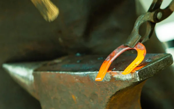 Blacksmith forges a hot horseshoe — Stock Photo, Image