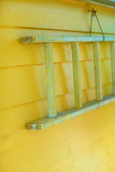 Escalera de madera colgada en la pared de la casa amarilla — Foto de Stock