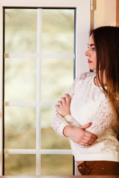 Vrouw die door het raam kijkt — Stockfoto