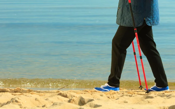 Vrouw nordic-walking op een strand — Stockfoto