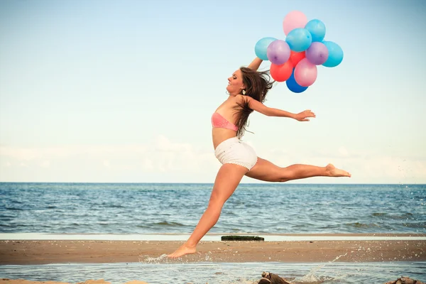 Mädchen springt mit bunten Luftballons — Stockfoto