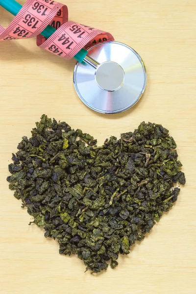 Grönt te lämnar hjärtformade och stetoskop — Stockfoto