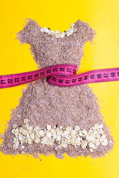 Dress shape made from bran with measure tape — Stock Photo, Image