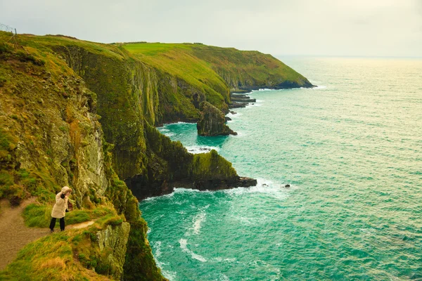 Irish atlantic coast. Woman tourist standing on rock cliff — Stock Photo, Image