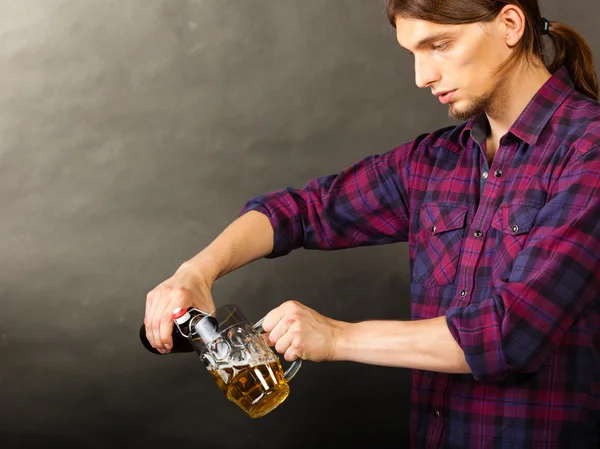 Young man pouring beer from bottle into mug — Stock Photo, Image