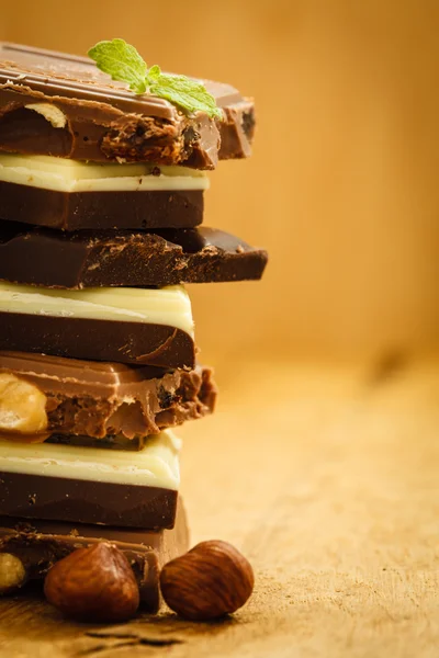 Stack of different sorts chocolate and hazelnuts — Stock Photo, Image