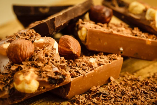 Chocolate shavings and pieces on wooden table — Stock Photo, Image