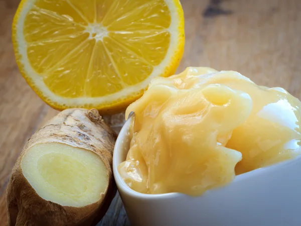 Корень имбиря, мед и лимон на деревянном деревенском столе. — стоковое фото