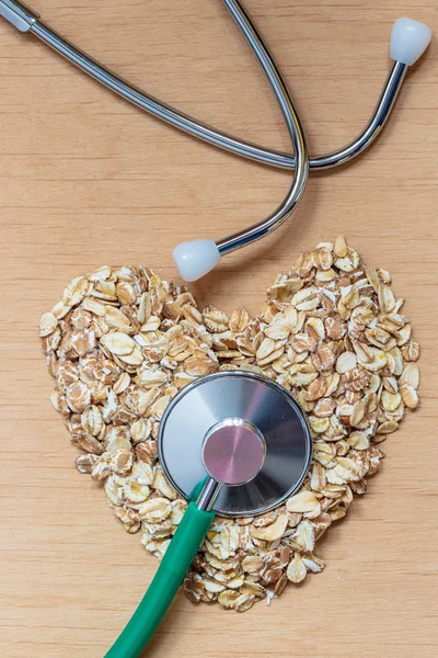 Oat flakes heart shaped and stethoscope. — Stock Photo, Image