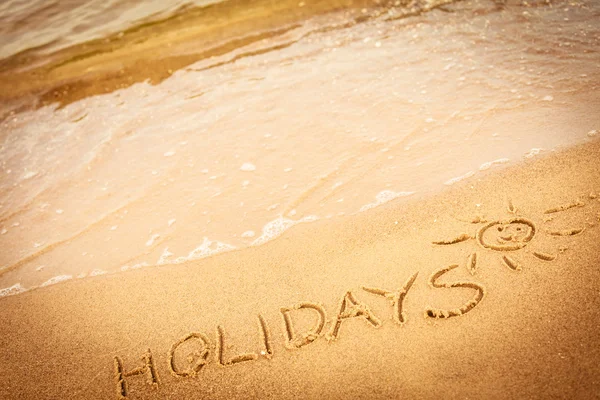 De vakantie van de woord geschreven in het zand op een strand — Stockfoto