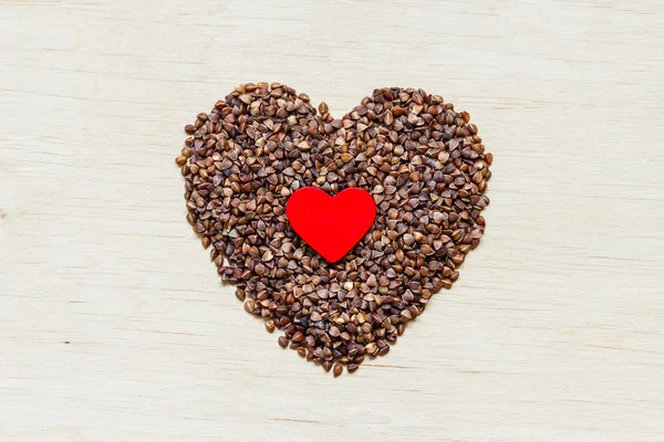 Grañones de trigo sarraceno corazón en forma de superficie de madera. —  Fotos de Stock